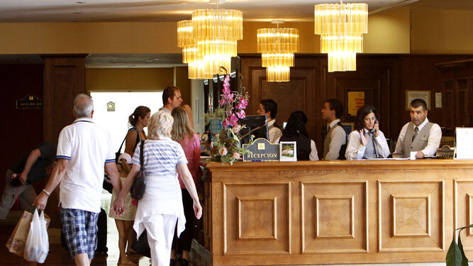 Varios turistas y empleados de un hotel andaluz en la recepción.