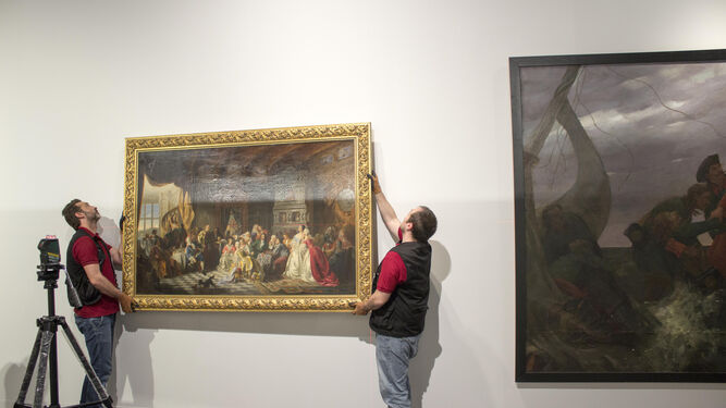 Dos montadores colocan uno de los cuadros de la muestra 'La dinastía Románov'.