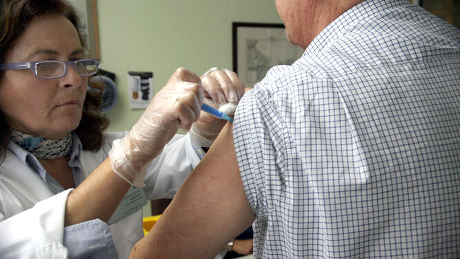 Una sanitaria vacuna a un paciente.