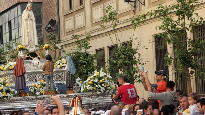 Los turistas aprovechan cualquier espacio para fotografiar la procesión de la Virgen de Fátima.