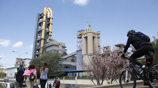 Varias personas pasan cerca de la fábrica de cemento de La Araña.
