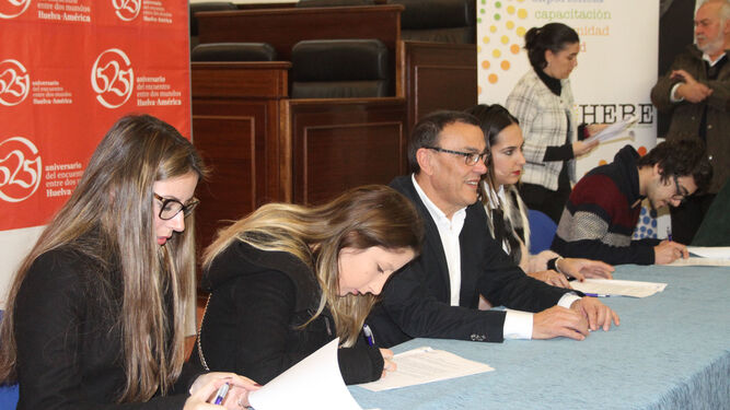 Varios jóvenes firman la beca del Plan HEBE junto a Ignacio Caraballo.