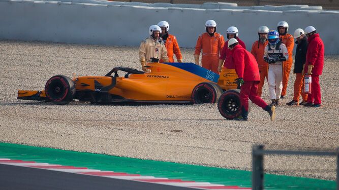 Un operario lleva la rueda junto al McLaren de Alonso.