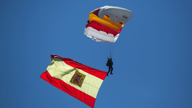 Un paracaidista desciende en el cielo malagueño con la bandera de España.