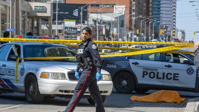 Una policía canadiense observa la zona del atropello en Toronto mientras pasa junto a una de las víctimas mortales.