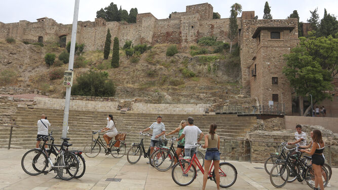 Un grupo de turistas en la calle Alcazabilla, con las vistas del Teatro Romano y la Alcazaba.