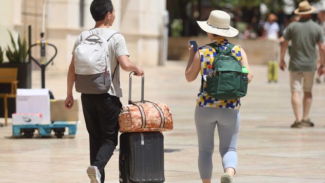 Un par de turistas con su equipaje por el centro de Málaga.