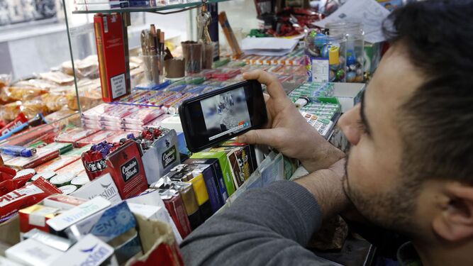 Un iraní observa las noticias en su móvil en un quiosco de Teherán.