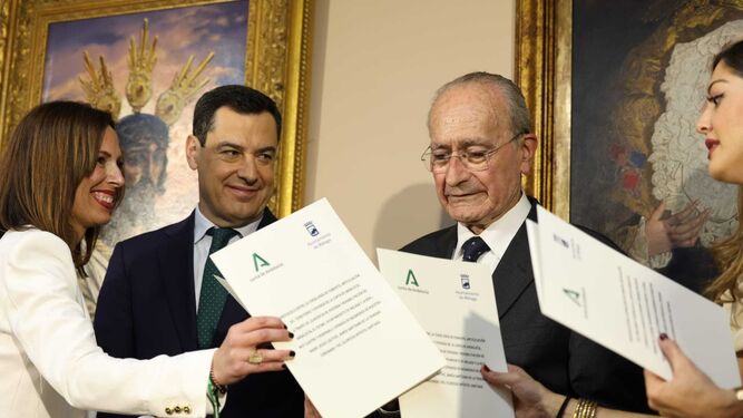 En el centro, Juanma Moreno, presidente de la Junta de Andalucía, y Francisco de la Torre, alcalde de Málaga, intercambian los documentos para la cesión.