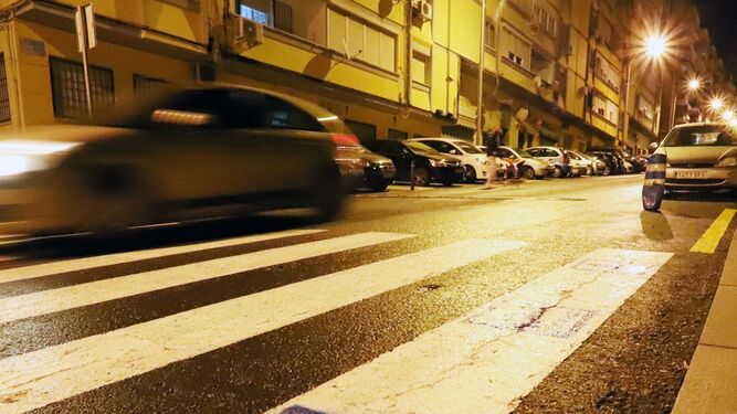 Un coche pasa por un paso de peatones en Huelva por la noche.