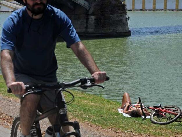 Un ciclista por el r&iacute;o con una joven tumbada en el c&eacute;sped de la orilla junto.

Foto: Victoria Hidalgo/Juan Carlos V&aacute;zquez