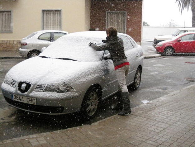 Una joven limpia la nieve acumulada en un coche en Constantina.

Foto: C. Valdivieso
