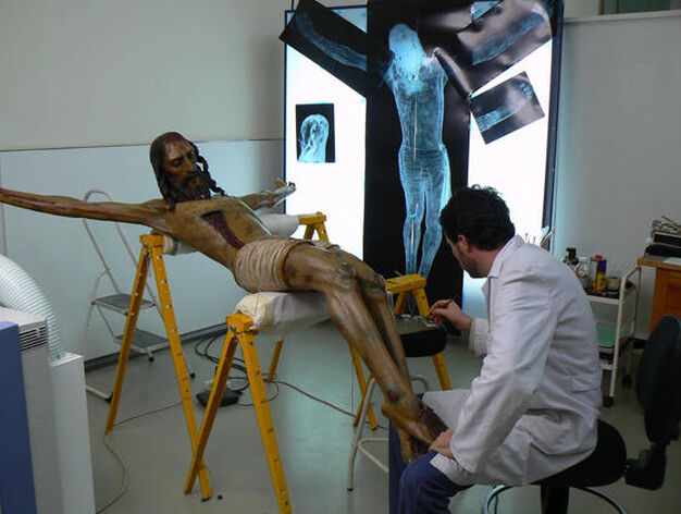 Un restaurador del taller de escultura trabaja sobre la talla del Crucificado de Bornos, en C&aacute;diz, con varias radiograf&iacute;as al fondo.

Foto: Ruesga Bono
