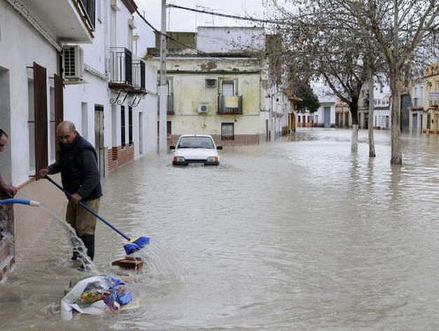 Varios vecinos de Lora del R&iacute;o usan mangueras y escobas para achicar el agua que inunda sus casas. 

Foto: Juan Carlos V&aacute;zquez