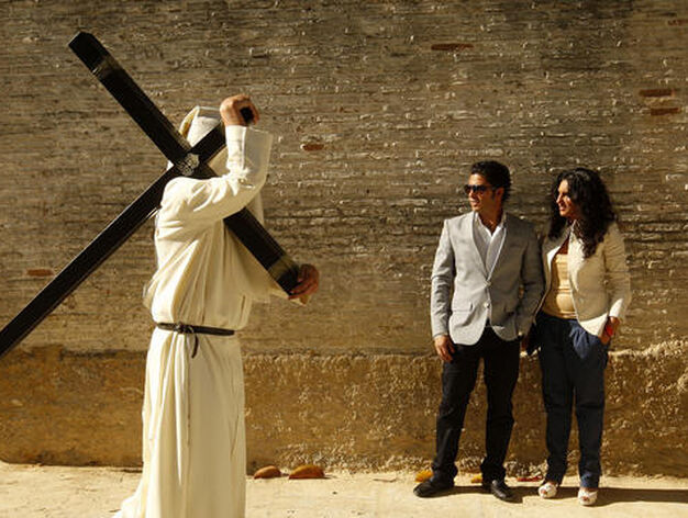 Un penitente pasa junto a una pareja que contempla el discurrir de la hermandad.

Foto: Juan Carlos Toro