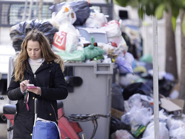 Una mujer mira el tel&eacute;fono al lado de un contenedor repleto de basura.

Foto: Maril&uacute; B&aacute;ez