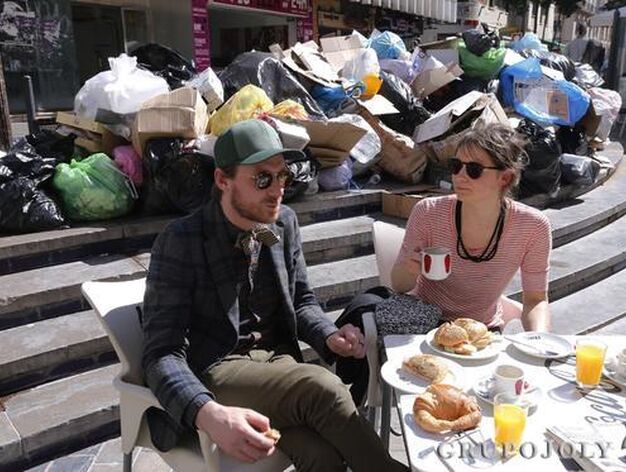Dos turistas en la plaza de la Merced, repleta de bolsas de basura.

Foto: Javier Albi&ntilde;ana