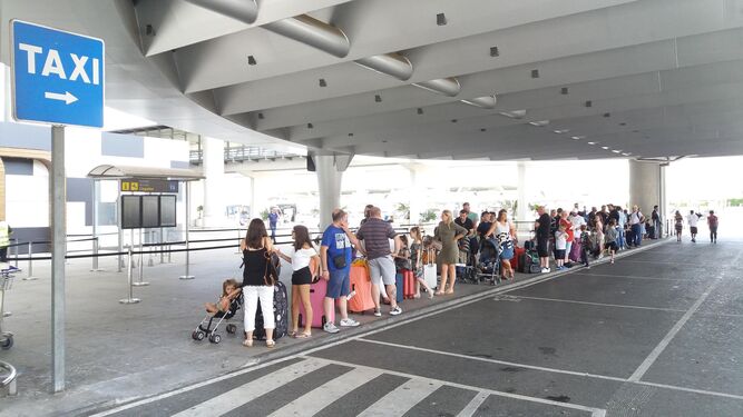 Turistas esperan en el aeropuerto la llegada de un taxi.