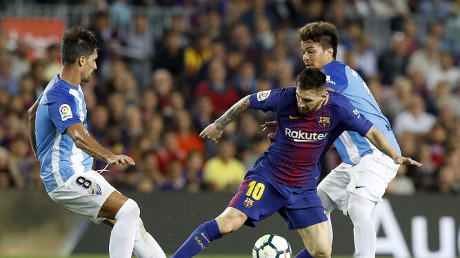 Messi protege el balón ante dos jugadores del Málaga