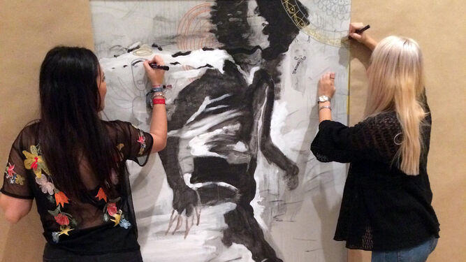Dos mujeres trabajan en el gran mural que se expodrá mañana.