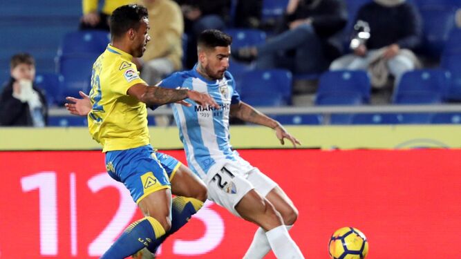 El defensa uruguayo de la UD Las Palmas Matías Aguirregaray salta por el balón con el venezolano Roberto Rosales, del Málaga CF.
