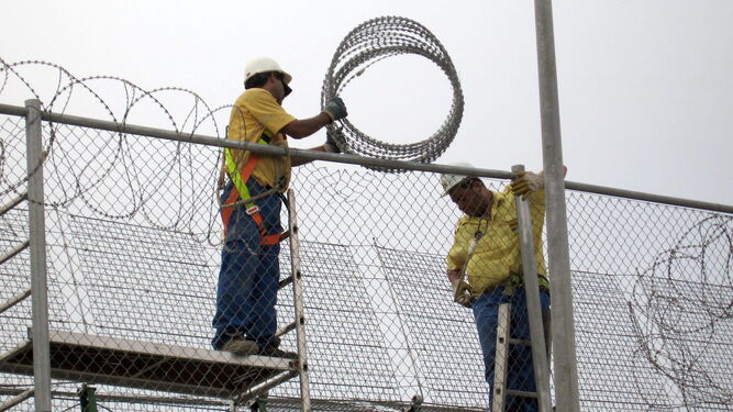 Dos operarios reparan las concertinas en la valla de Melilla, en la frontera entre España y Marruecos.