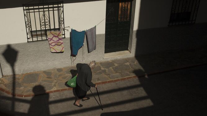 Una señora mayor pasea por una de las calles de Pujerra.