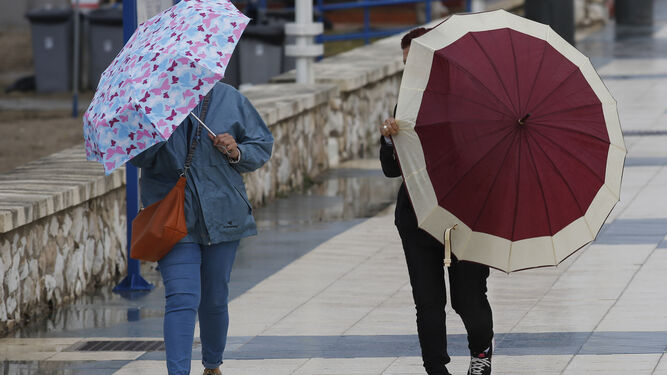 Dos personas caminan con sus paraguas.