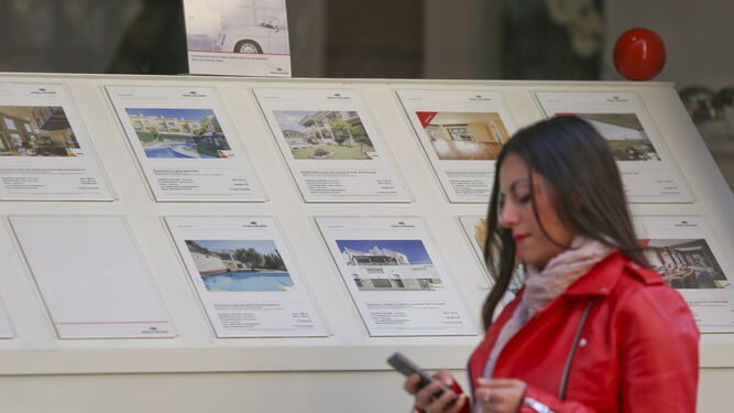 Una mujer pasa junto a una agencia inmobiliaria en Málaga capital.