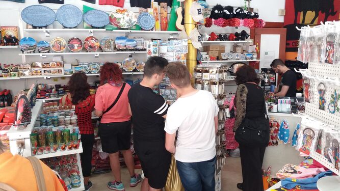 Turistas miran 'souvenirs' en el establecimiento Souvenirs Victoria de la calle Molina Lario.