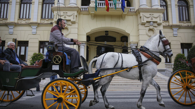 Un coche de caballos pasa frente a la sede del Ayuntamiento de Málaga.s