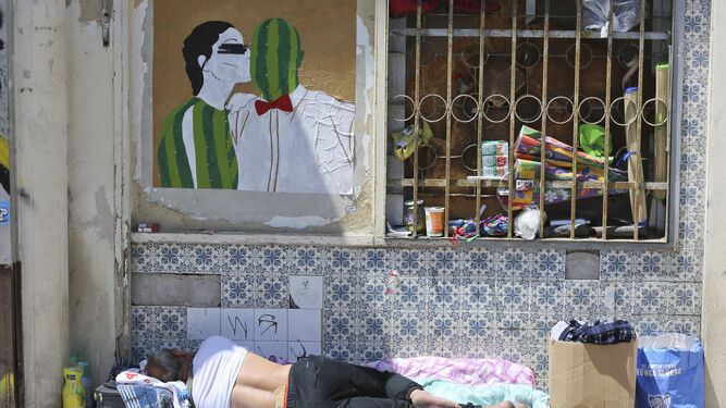 Una persona duerme al sol y junto a sus pertenencias en una calle de la capital malagueña.