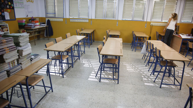 Una maestra baja las persianas de un aula vacía.