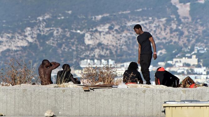 Inmigrantes subsaharianos descansan en la dársena del Saladillo, ayer, en Algeciras.