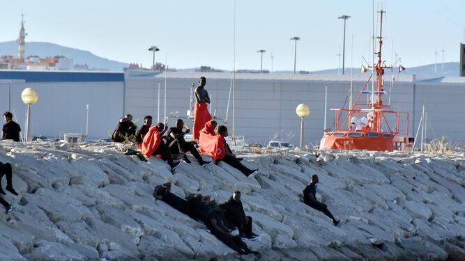 Varios migrantes esperan en el muelle del Saladillo a ser reubicados tras ser rescatados del mar.