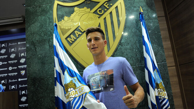 El futbolista posa con la bandera del Málaga en la sala de prensa.