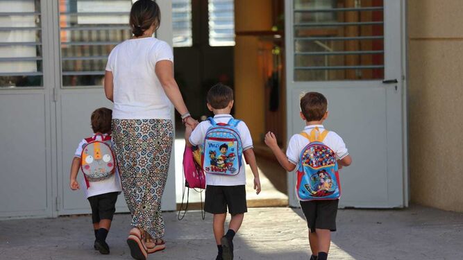 Niños entrando a un colegio de Málaga acompañados por una docente