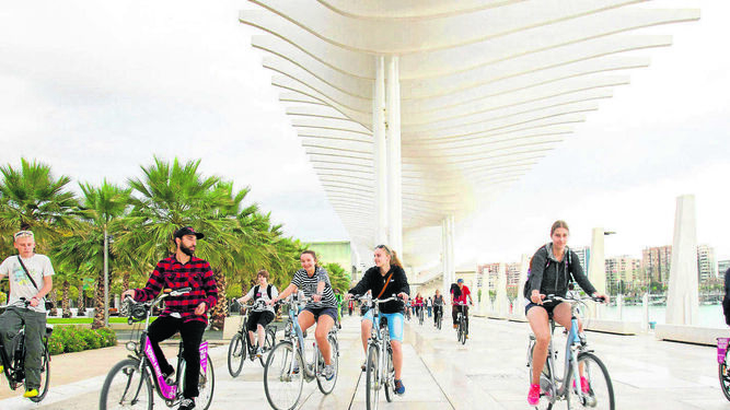 Jóvenes disfrutando del puerto de Málaga en bicicleta.