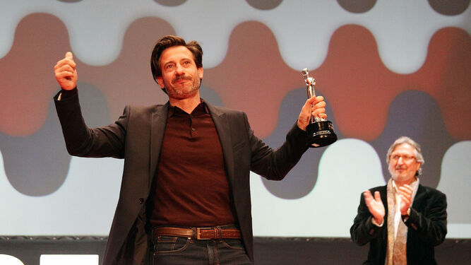 El actor Alfonso Tort, aplaudido por Sebastián Haro, recibe el reconocimiento del público con su Colón de Plata al Mejor Actor por ‘La noche de 12 años’ en las manos.