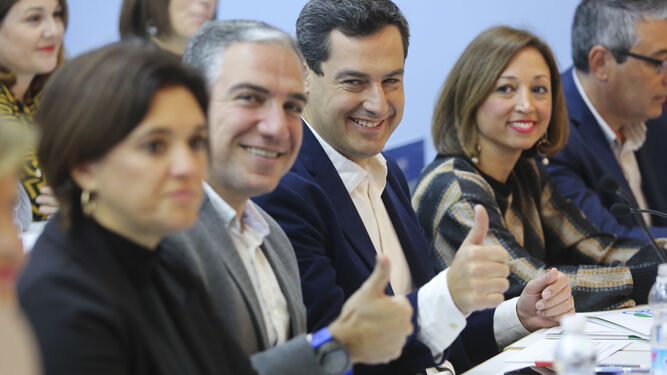 Bendodo y Moreno saludan en la Junta Directiva del PP de Málaga junto a compañeros de partido.