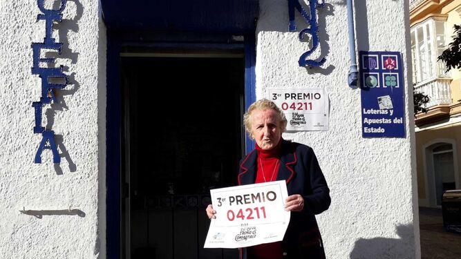 El número agraciado con el tercer premio se ha vendido también en la calle Real. En la imagen, Pilar Sevillano con el cartel del número premiado.
