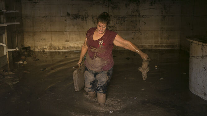 Una mujer ayuda a recoger pertenencias de un garaje inundado de Campillos.