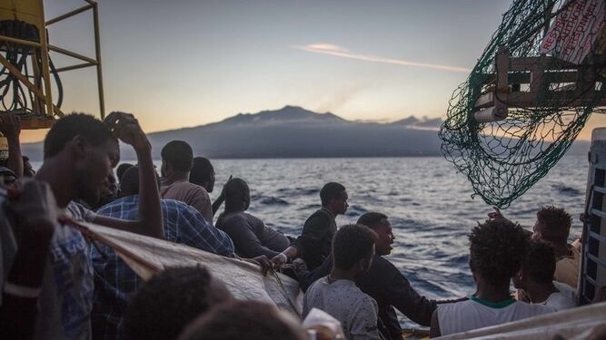 Los migrantes esperan en el barco con la localidad italiana de Siracusa a la vista.