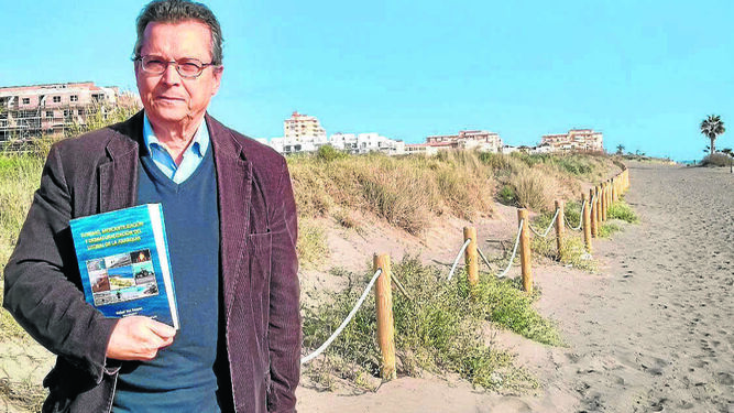 Rafael Yus posa para esta entrevista con su libro junto a las dunas de El Morche.