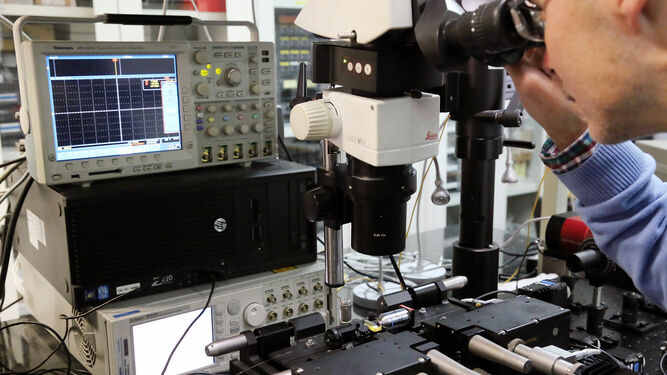 Un investigador observa un chip con un microscopio en el Laboratorio de Fotónica y Radiofrecuencia de la UMA.