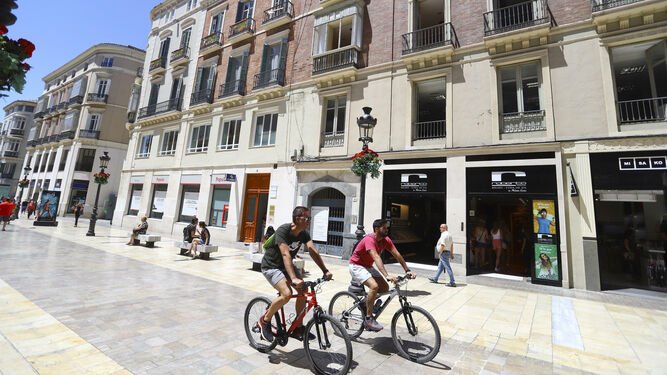 Dos ciclistas pasan por la calle Larios, junto a la fachada del edificio número 10.