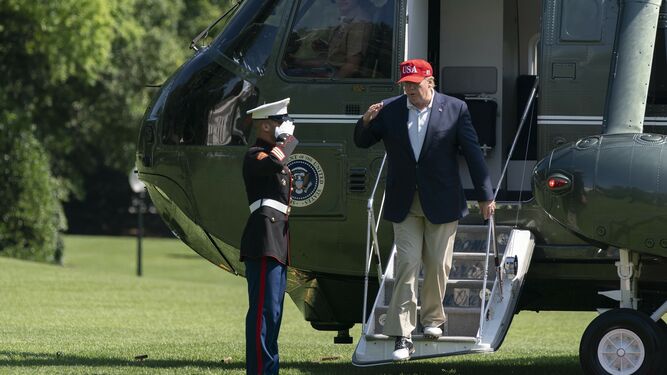 Trump saluda a un soldado mientras baja de su helicóptero.