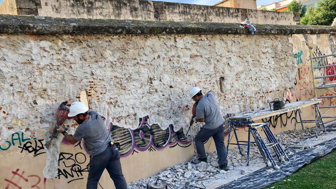 Operarios limpian uno de los grafitis en Rincón de la Victoria