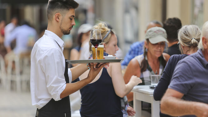 Un camarero atiende unas mesas.