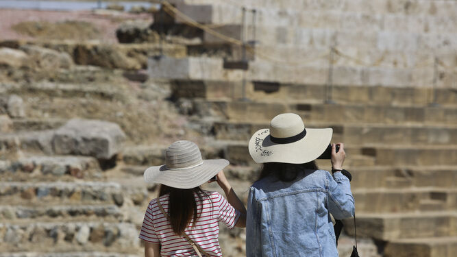 Dos turistas se protegen del sol con un sombrero.